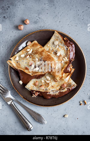 Crepes con diffusione di cioccolato e nocciole. In casa crespelle sottili per la prima colazione o per dessert, vicino. Foto Stock