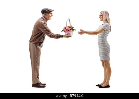 A piena lunghezza shot di un anziano uomo dando un cesto con fiori di una giovane donna isolato su sfondo bianco Foto Stock