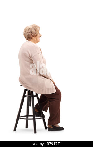 A piena lunghezza shot di un senior donna seduta su una sedia sgabello e posa isolati su sfondo bianco Foto Stock