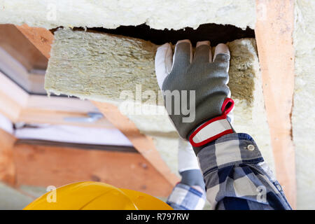 L'uomo installazione tetto termica dello strato di isolamento - utilizzando pannelli in fibra minerale. Soffitta il rinnovamento e il concetto di isolamento Foto Stock
