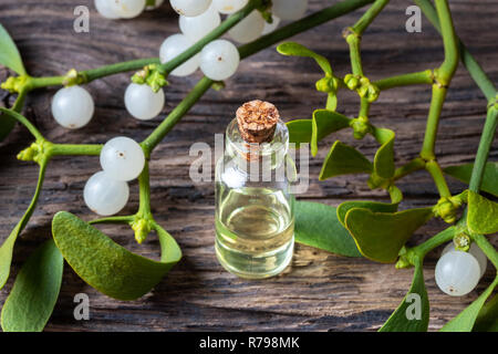 Una bottiglia di olio essenziale con freschi ramoscelli di vischio Foto Stock