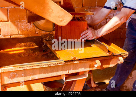 Lavoratore è l'utilizzo di power tool per pulire rende preciso taglio in rosso mattone, blocco. Esso utilizza azione abrasiva per slice attraverso il materiale come la lama ruota a hig Foto Stock