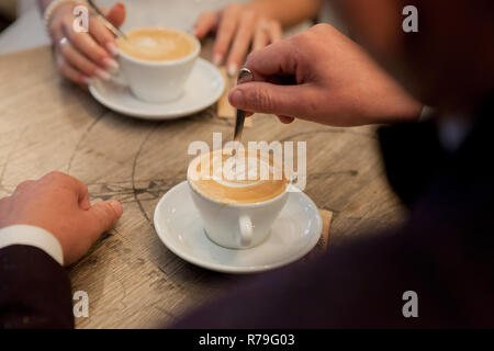Sposa e lo sposo accogliere tazze con cappuccino e guardare a ogni altro. Foto Stock