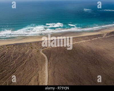 Vista aerea della spiaggia di Famara, Lanzarote, Isole Canarie, Spagna. Risco di Famara, rilievo, montagne che si affacciano sull'Oceano Atlantico. Strada sterrata Foto Stock