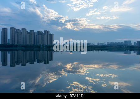 Come il sole tramonta, la bella nuvole e cielo riflette sulle calme acque di Wuhan, Cina su un atipico meteo e inquinamento giorno. Stupendo! Foto Stock