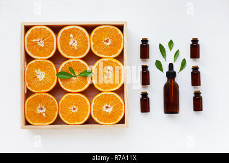 Bottiglia di olio essenziale di arance agrumi con succo di arancia e foglie su sfondo bianco, medicina alternativa Foto Stock