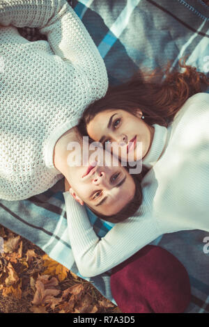 Bella coppia Giovane è giacente in autunno park e guardando interessati nel cielo Foto Stock