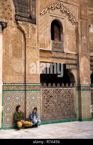 Il Marocco, Fes, Fes el Bali, Medina, Talaa Seghira, Medersa Bou Inania, giovani turisti sat nel cortile circondato da altamente decorato le pareti Foto Stock