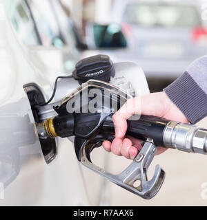 Primo piano della mano mans pompando benzina in auto alla stazione di gas. Foto Stock