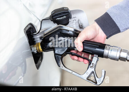 Primo piano della mano mans pompando benzina in auto alla stazione di gas. Foto Stock