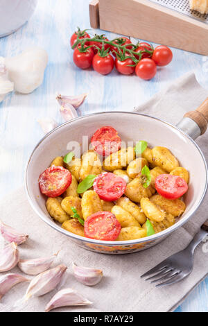 Gnocchi al forno con pesto verde,pomodorini e scaglie di parmigiano Foto Stock