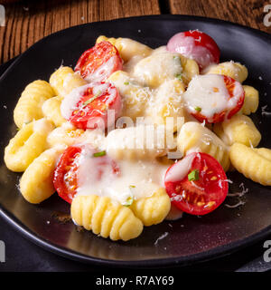 Gnocchi al forno con pesto verde,pomodorini e scaglie di parmigiano Foto Stock