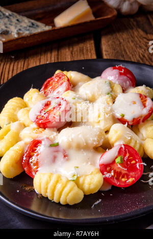 Gnocchi al forno con pesto verde,pomodorini e scaglie di parmigiano Foto Stock