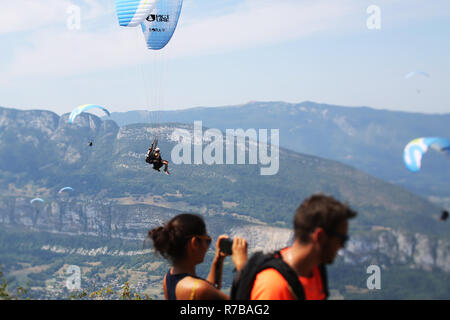 Un pilota di tandem e i suoi passeggeri battenti nella parte anteriore del Col de la Forclaz decollo. Annecy, Francia Foto Stock