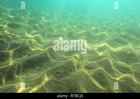 Fondo del mare, sabbia 'dunes' illuminata dal sole, l'acqua turchese in distanza. Fotografia subacquea - abstract sfondo marino Foto Stock
