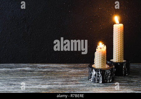 La masterizzazione di candele di cera su un vecchio tavolo di legno. Mistica scuro dello sfondo. Foto Stock