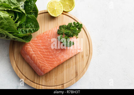 Materie filetto di salmone, lattuga e limoni su una cucina in legno bordo, elevato angolo vista da sopra, spazio copia selezionata, focus, profondità di campo ridotta Foto Stock