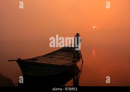 Uomo locale spostando barca sul fiume Yamuna con un palo di sunrise, Agra, Uttar Pradesh, India. Agra è una delle più popolose città in Uttar Pradesh Foto Stock
