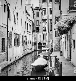 Lato stretto canale con barche ormeggiate a Venezia, Italia. Immagine in bianco e nero Foto Stock