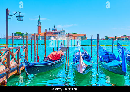 Paesaggio urbano veneziano con gondole attraccate e San Giorgio di maggiore chiesa in Venezia, Italia su soleggiate giornate estive Foto Stock