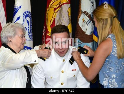 MADISON, Wisconsin, (maggio 13. 2017) - University of Wisconsin-Madison riserva navale addestramento ufficiali Corps (NROTC) Guardiamarina di prima classe Christopher Houben, 21, da Ginevra, Illinois, ha il suo U. S. Navy ensign schede di spalla segnato dalla sua nonna Phyllis Cooper e suor Victoria Houben durante un ROTC Servizio Congiunto ufficiale cerimonia di messa in servizio nella Sala Concerto del Gordon Dining & Event Center on campus, 13 maggio. I nove Navy e Marine Corps aspiranti guardiamarina, 10 Esercito e 16 Air Force cadetti sono state commissionate dopo la laurea inizio cerimonie terrà presso l'università del Camp Randal Foto Stock