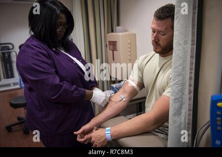 Un assistente medico aspira il sangue dal personale Sgt. Nicholas Worley, 23d' ingegnere civile Squadron impianti elettrici artigiano, durante un appuntamento, Aprile 18, 2017 in Valdosta, Ga. Nel gennaio 2012 Worley è stato diagnosticato con leucemia mielogena cronica, una rara forma di sangue di cellule di cancro che inizia nel sangue-la formazione di cellule di midollo osseo. Egli è attualmente in fase di remissione e passa per il centro del Cancer di ogni tre mesi per garantire il suo trattamento è ancora funzionante. Foto Stock