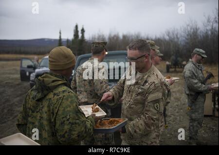 Stati Uniti Army Sgt. Il Mag. James Gaw, il 6° Brigata Battaglione ingegnere (airborne), Base comune Elmendorf Richardson, Alaska, il comando sergente maggiore, serve un U.S. Marine la sua cena durante il bordo settentrionale 2017 Maggio 09, 2017 a Fort Greely, Alaska. Per questa parte dell'esercizio di soldati e marines vissuto in Combat Training gamma per simulare che vivono in un ambiente distribuito. Foto Stock