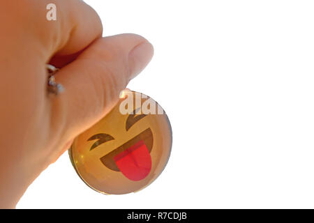 La mano trattiene un portachiavi giallo contro uno sfondo bianco . Sorriso mostra la linguetta, spensierata gioiosa vita Foto Stock