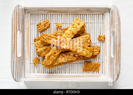 Tempeh fritto in un vassoio di bianco su una superficie di legno. Vista superiore Foto Stock