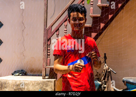 Don Daeng, Laos - Aprile 27, 2018: pescatore locale la riparazione di una rete da pesca nel cortile della sua casa in una zona rurale remota del Laos Foto Stock