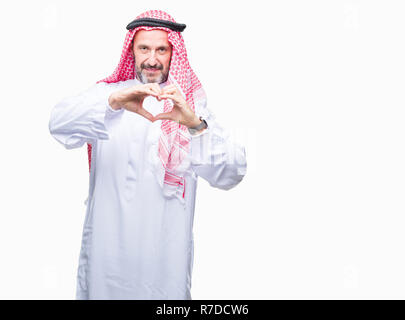 Senior uomo arabo indossando keffiyeh su sfondo isolato sorridente in amore che mostra il simbolo del cuore e la forma con le mani. Concetto romantico. Foto Stock