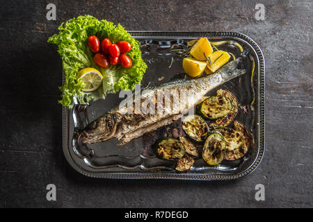 Pesce arrosto sul piatto con carni e verdure alla griglia. Foto Stock