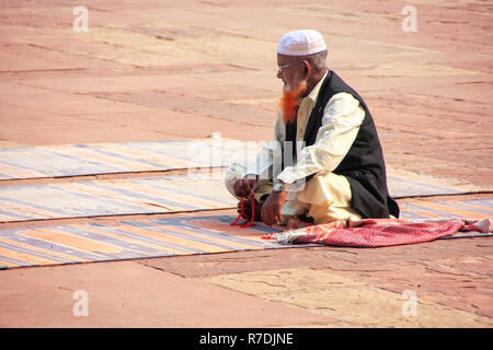 Local uomo seduto nel cortile della Jama Masjid in Fatehpur Sikri, Uttar Pradesh, India. La moschea è stata costruita nel 1648 dall'imperatore Shah Jahan e dedi Foto Stock