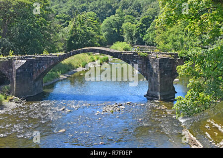 Vista del centro arco di pietra strette pack horse tre archi bridge & noto come Cromwells Ponte sul Fiume Hodder Hurst Green Lancashire England Regno Unito Foto Stock