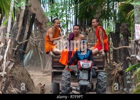 Don Daeng, Laos - Aprile 27, 2018: giovani monaci buddisti seduto su un trattore circondata da una foresta in una remota isola rurale sul fiume Mekong Foto Stock
