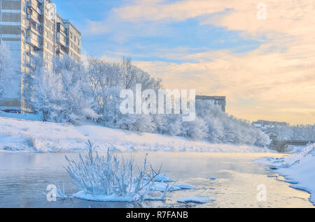 Bella e soleggiata inverno il paesaggio urbano in frozen snowy città sulla sponda del fiume, dove gli alberi sulla riva con il bianco hoarftost coperti, Novokuznetsk, Foto Stock