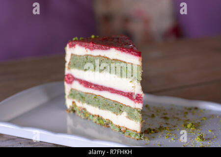 Il pistacchio e frutti di bosco torta su piastra bianca sulla tavola di legno Foto Stock