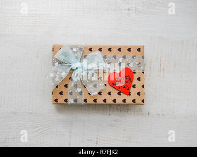 Scatola con un dono, legata con un nastro, nota con parole dolci Foto Stock