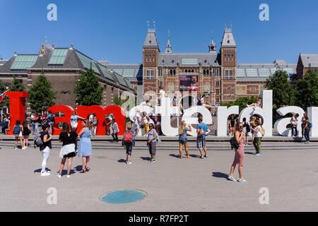 I turisti di fronte iconico ho amsterdam lettere con il Rijksmuseum in background, Amsterdam, Paesi Bassi Foto Stock