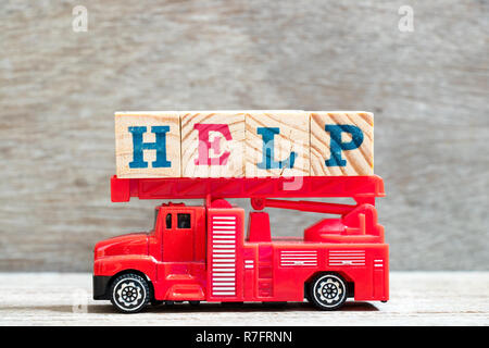 Toy red fire scala a carrello attesa blocco lettera nella parola help su uno sfondo di legno Foto Stock
