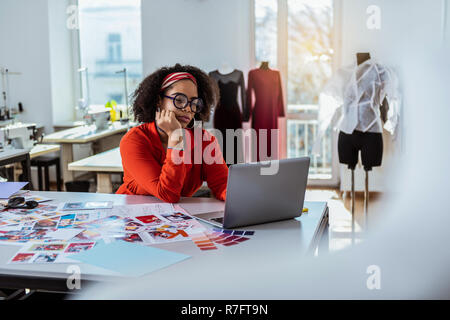 Ricci occupato dai capelli designer di trascorrere del tempo con il computer portatile Foto Stock