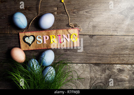 Le uova di pasqua su fresco erba verde su sfondo di legno con Sunny fasci di luce. Orizzontale con copia spazio. La pasqua o il concetto di primavera. Foto Stock