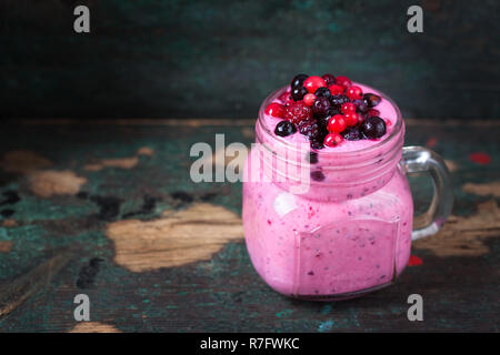 Freschi Fatti in casa frullato di yogurt selvatica selvatica bacche in un vaso di vetro su un vecchio sfondo vintage, primo piano Foto Stock