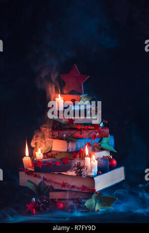 Albero di Natale fatto di libri con candele e misterioso fumo. Inverno decorazioni per lettori e nerds concept Foto Stock
