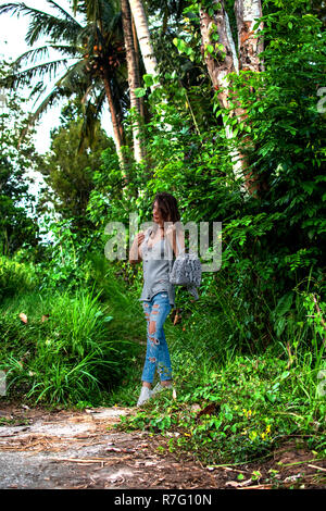 Style ragazza camminare con piccola borsa nella giungla. Concetto di stile, la moda di avventura e di viaggio con python accessorio Foto Stock