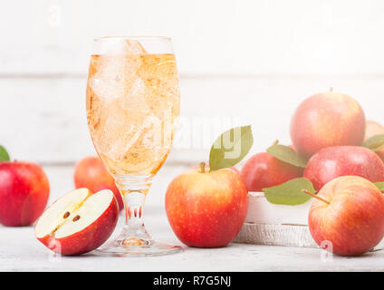 Bicchiere di organico in casa sidro di mele con mele fresche nella casella su sfondo in legno e vetro con cubetti di ghiaccio Foto Stock