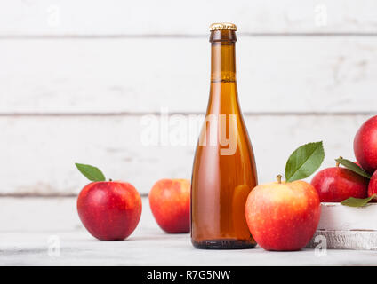 Bottiglia e bicchiere di organico in casa sidro di mele con mele fresche nella casella su sfondo in legno e vetro con cubetti di ghiaccio Foto Stock