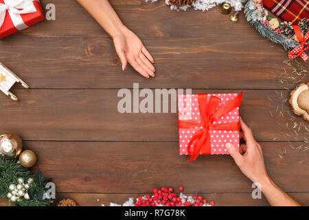 Nuovo anno. L uomo dando presente a donna isolato su decorate table top view close-up Foto Stock
