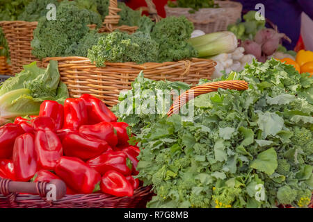 Peperoni rossi con un verity di verdura verde visualizzato al mercato verde. L'outdoor green market ha molti cestini di freschi prodotti biologici. Foto Stock