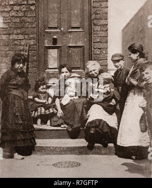 La vita per la lavorazione di folk in stile vittoriano giorni... Una famiglia seduta sui gradini della loro casa in Curzon Street Liverpool, Merseyside England Foto Stock